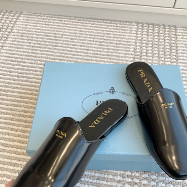 MULES IN BLACK GLOSSY SHEEPSKIN GOLD LETTERING LOGO